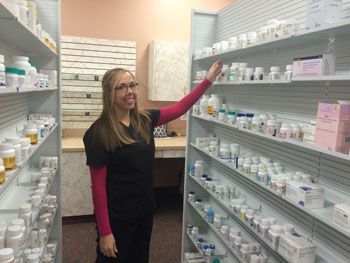 Woman in a pharmacy aisle reaching for a product on a shelf