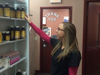 Woman reaching for medicine bottles on pharmacy shelf; 
