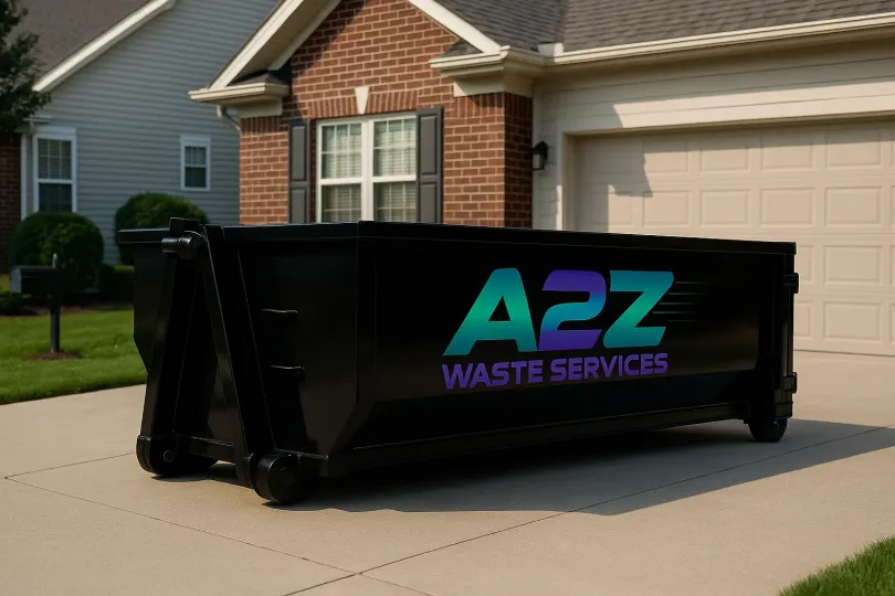 Black A2Z Waste Services dumpster parked on a driveway in front of a house.