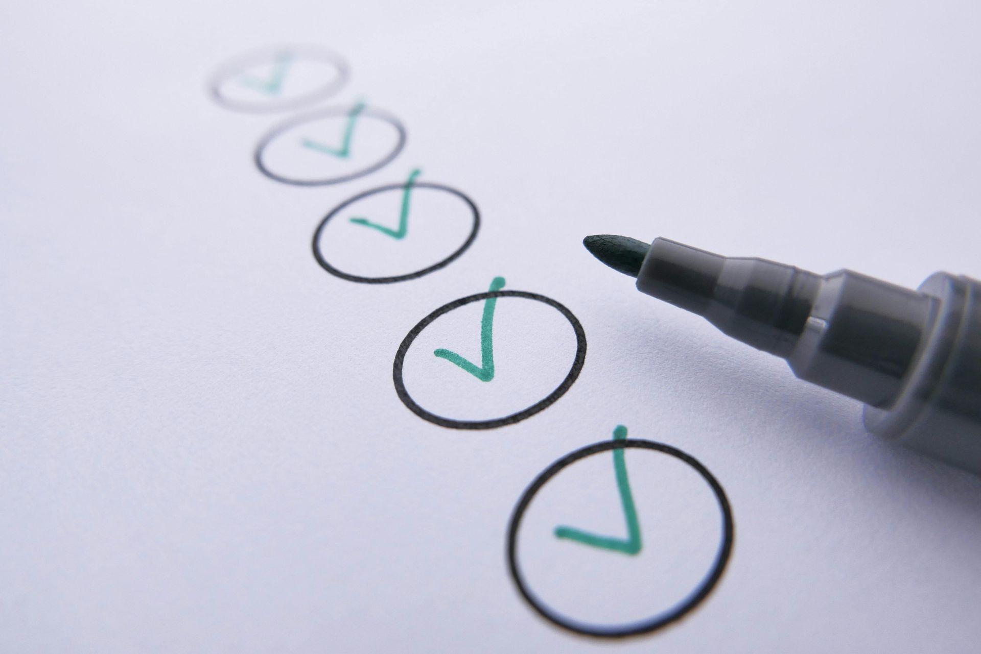 Pen checking off a list of circular checkboxes on paper