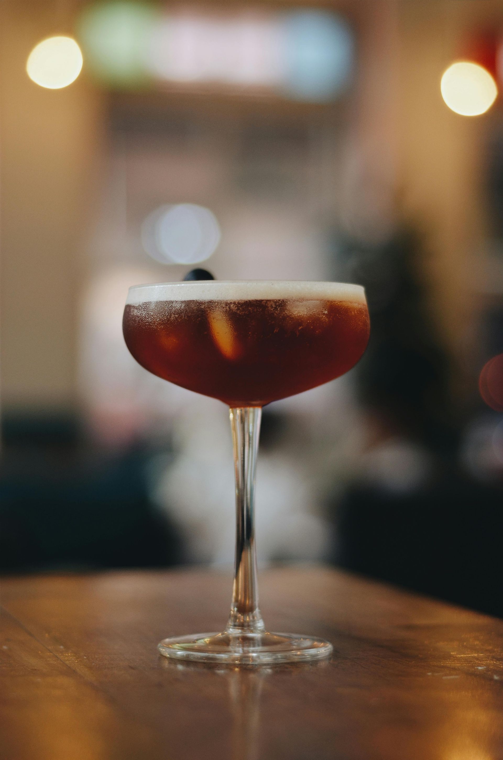 A close up of a cocktail in a coupe glass on a table.