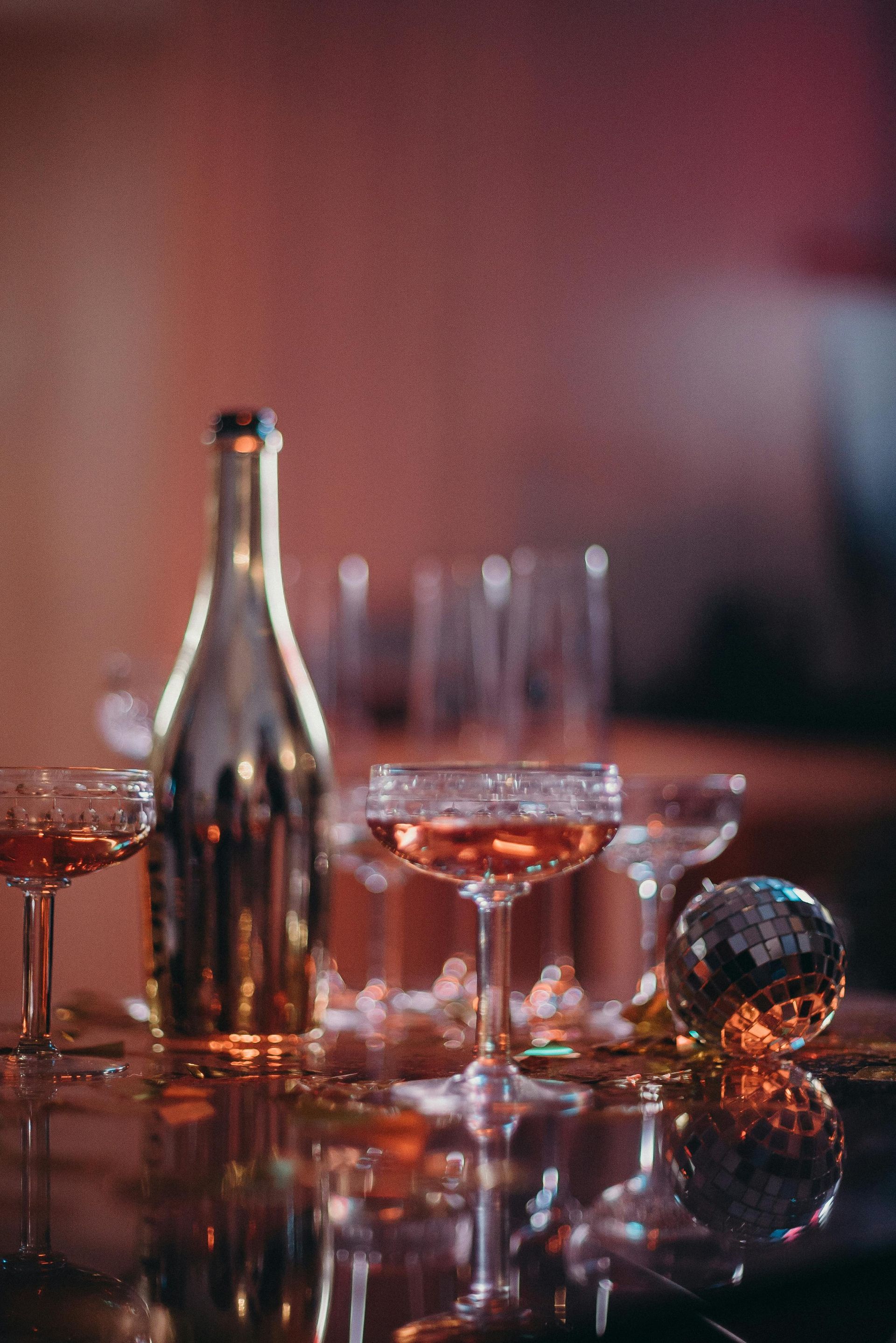 A bottle of wine and wine glasses are on a table.