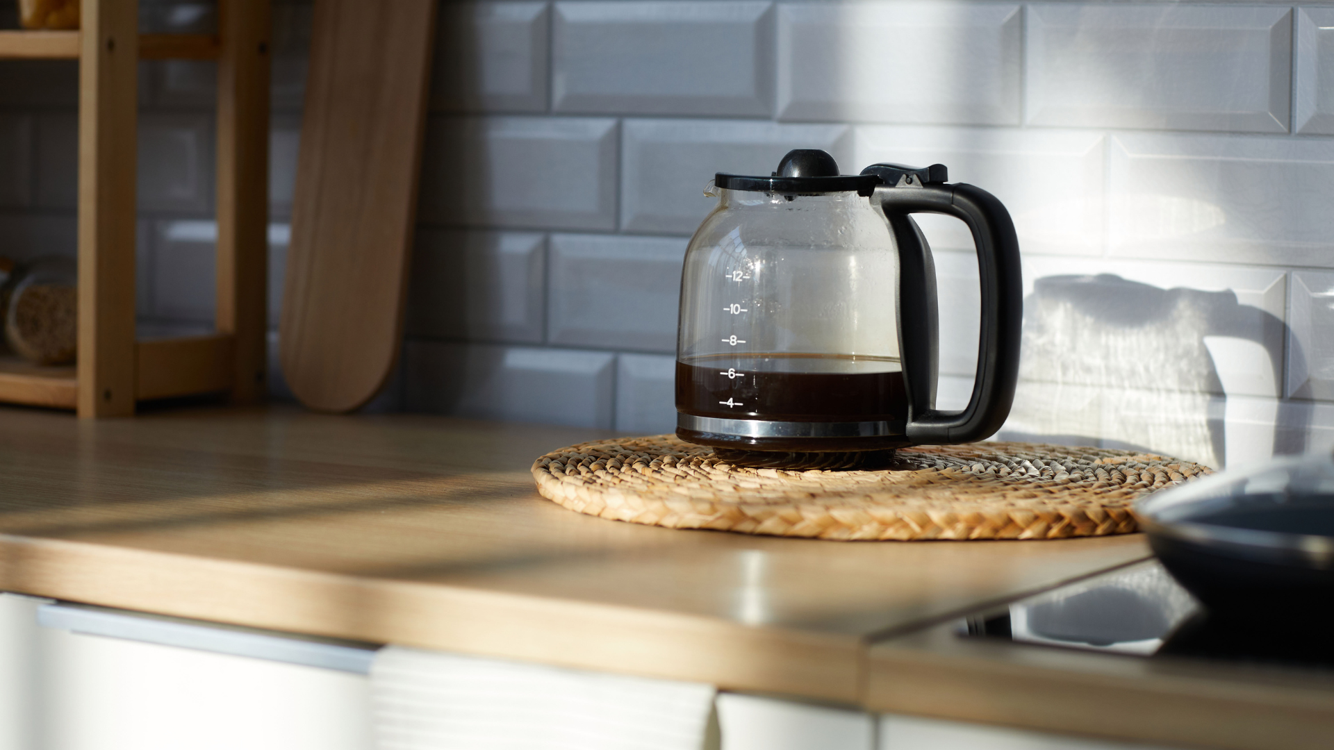 A coffee pot is sitting on a wooden counter in a kitchen.