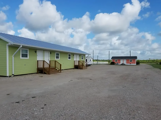 A green house with a blue roof is next to a red house.