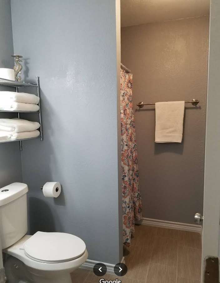 A bathroom with a toilet a shower and a towel rack