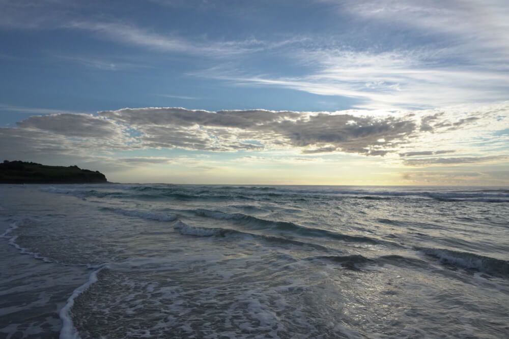 A Beach With Waves Crashing Against the Shore at Sunset — Bevan Plumbing in Ballina, NSW