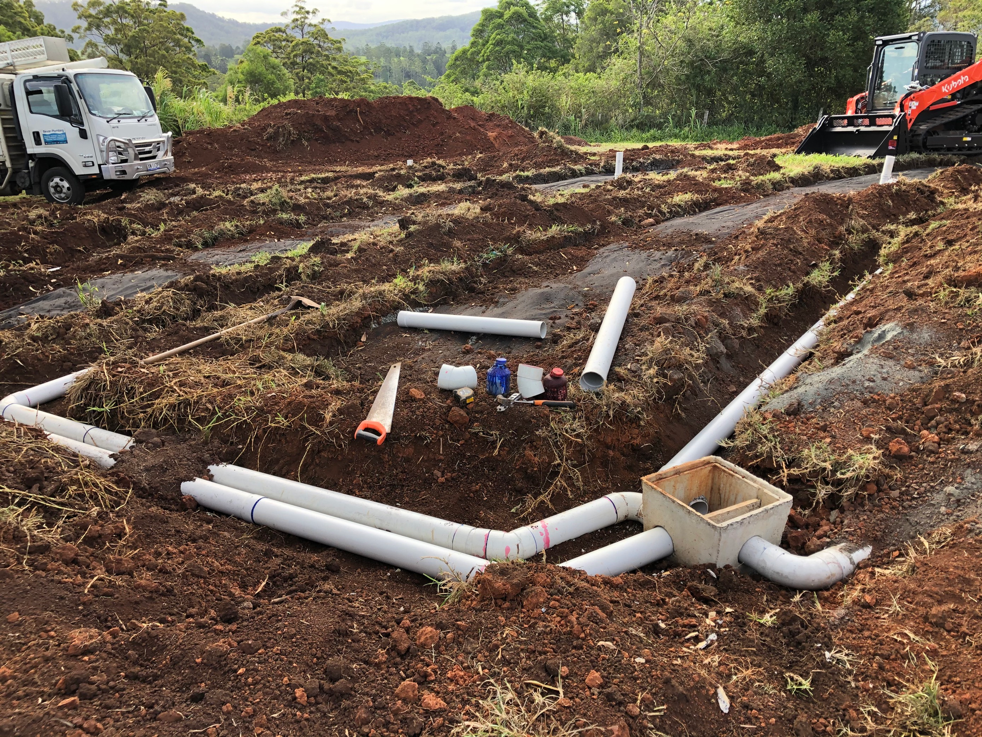 A Bunch of Pipes Are Laying in the Dirt in a Field — Bevan Plumbing in South Lismore, NSW