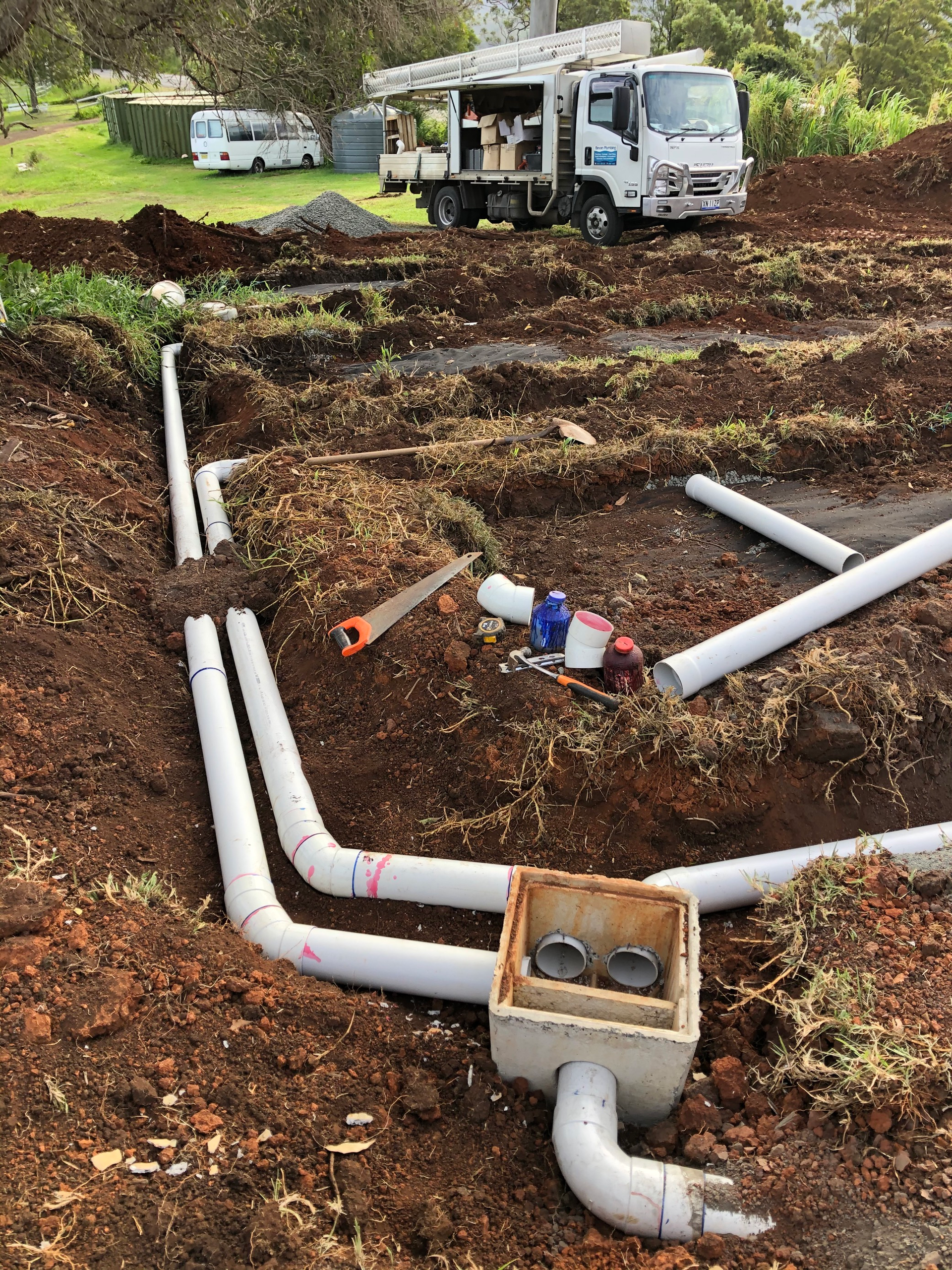 A Truck is Parked in the Dirt Next to a Pile of Pipes — Bevan Plumbing in South Lismore, NSW