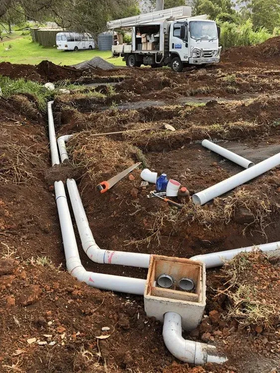 A Bunch of Pipes Are Laying in the Dirt on a Construction Site — Bevan Plumbing in South Lismore, NSW