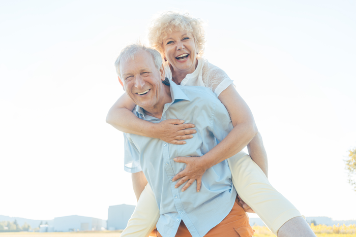 A man is carrying a woman on his back in a field.