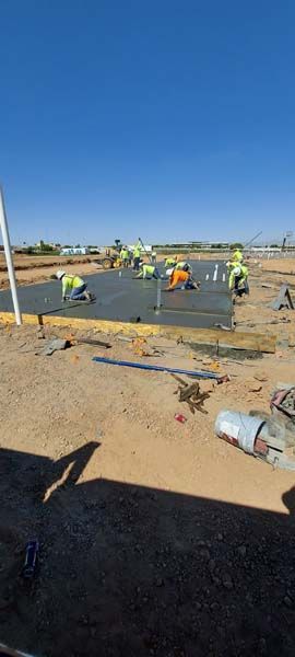 Construction workers smoothing wet concrete on a bright, sunny day.