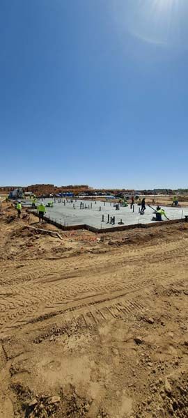 Construction workers pouring concrete foundation on a sunny day.