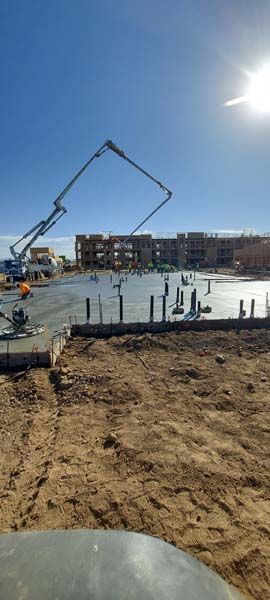 Construction site: concrete being poured for a building foundation; blue sky, sunny day.