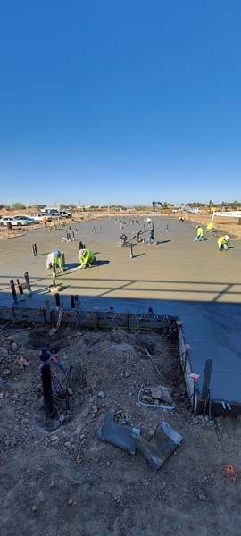 Construction workers pouring and smoothing concrete on a sunny day.