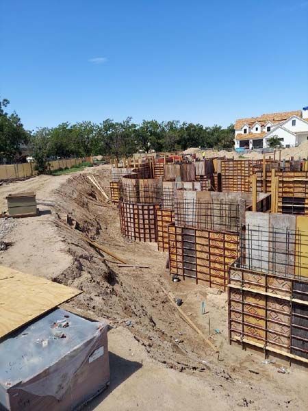Construction site with concrete forms and exposed earth, under a blue sky.