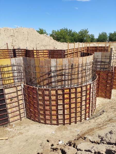 Circular concrete forms in a construction site, awaiting concrete pouring. Brown and yellow colors.