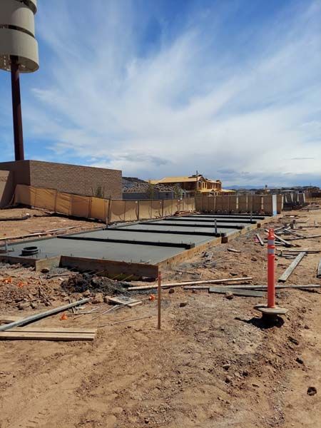 Construction site with concrete foundations; brown dirt; blue sky.