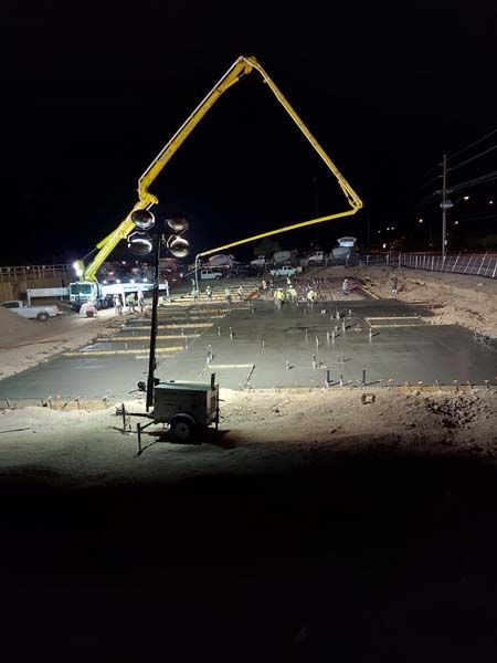 Concrete pouring at night; mobile lights illuminate a construction site with a pump truck.