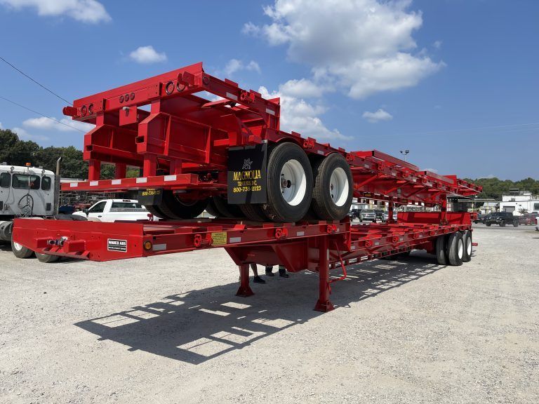 Red poultry trailer parked outdoors on gravel.
