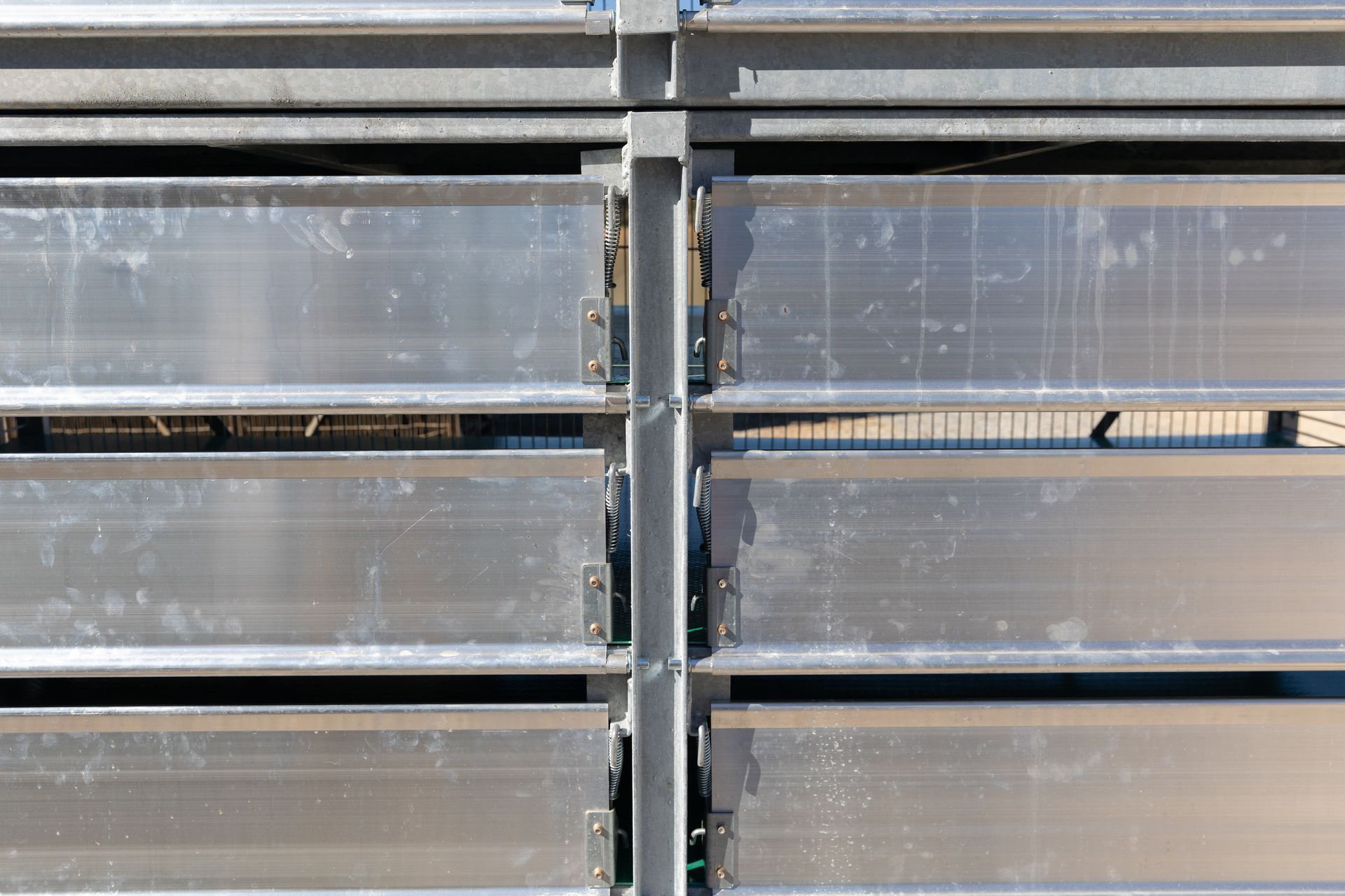 Horizontal metal slats, likely a fence or wall, joined by vertical support beams.