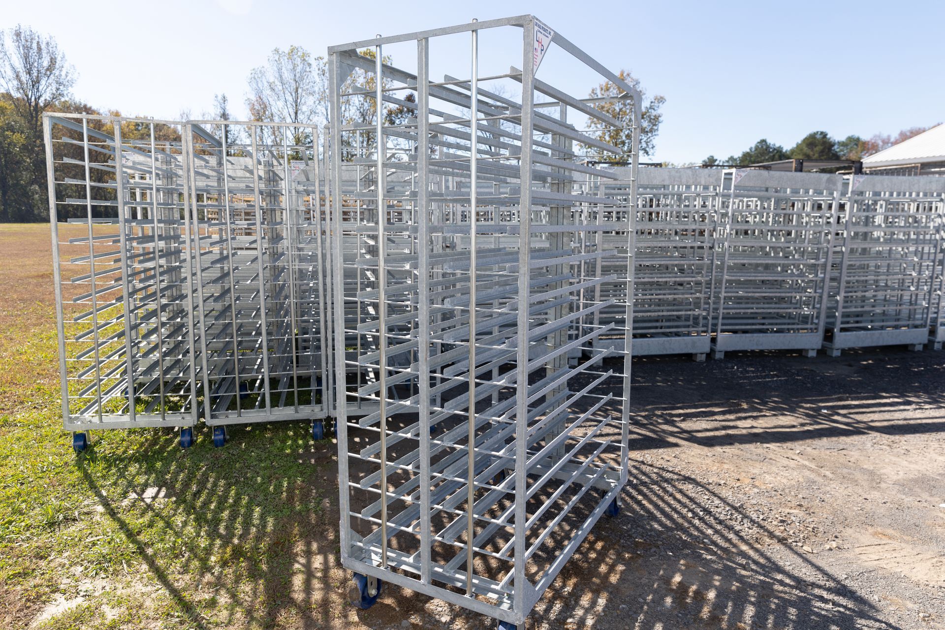 Metal racks on wheels, stacked outdoors, likely for storage or transport.