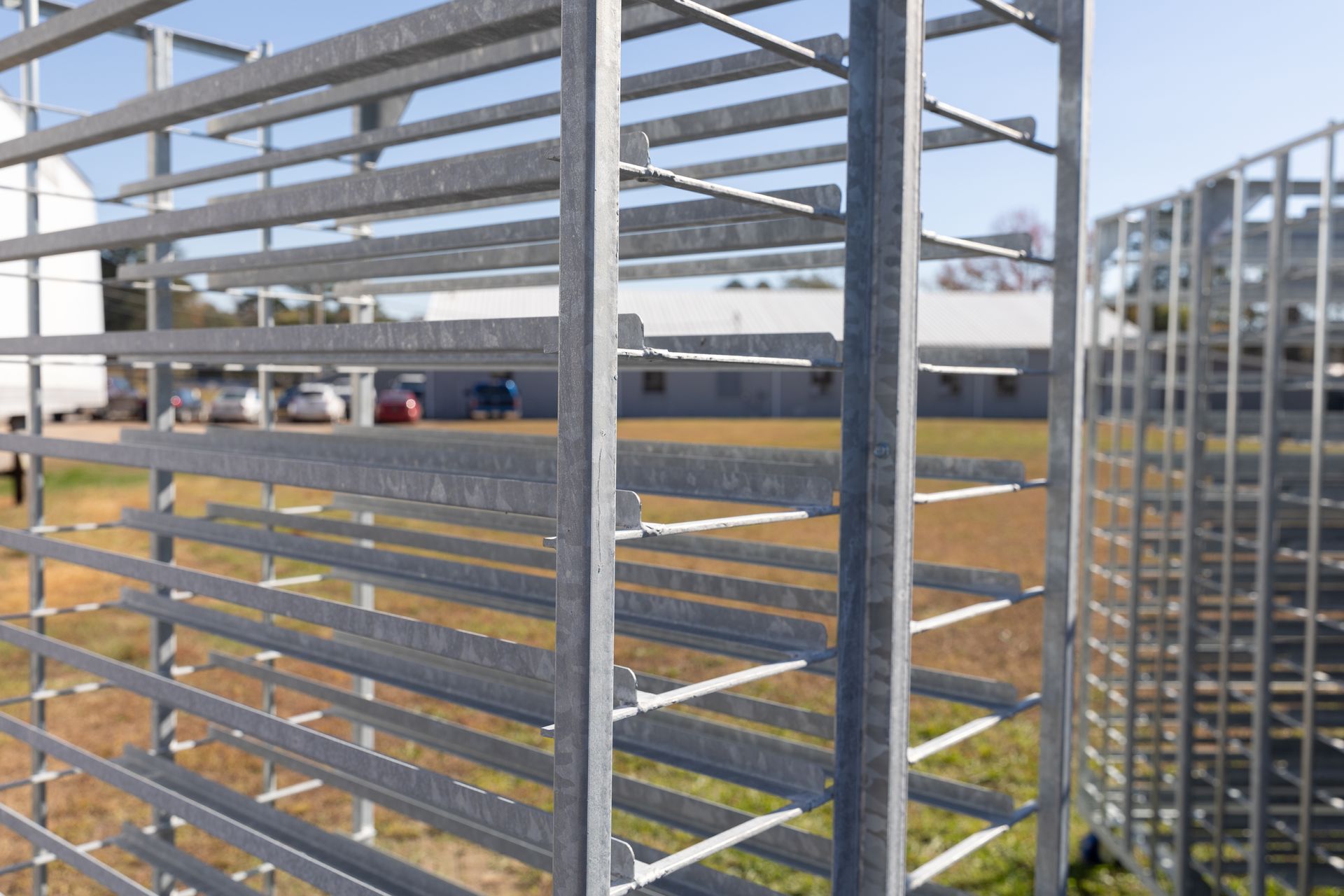 Metal racks on wheels, stacked outdoors, likely for storage or transport.