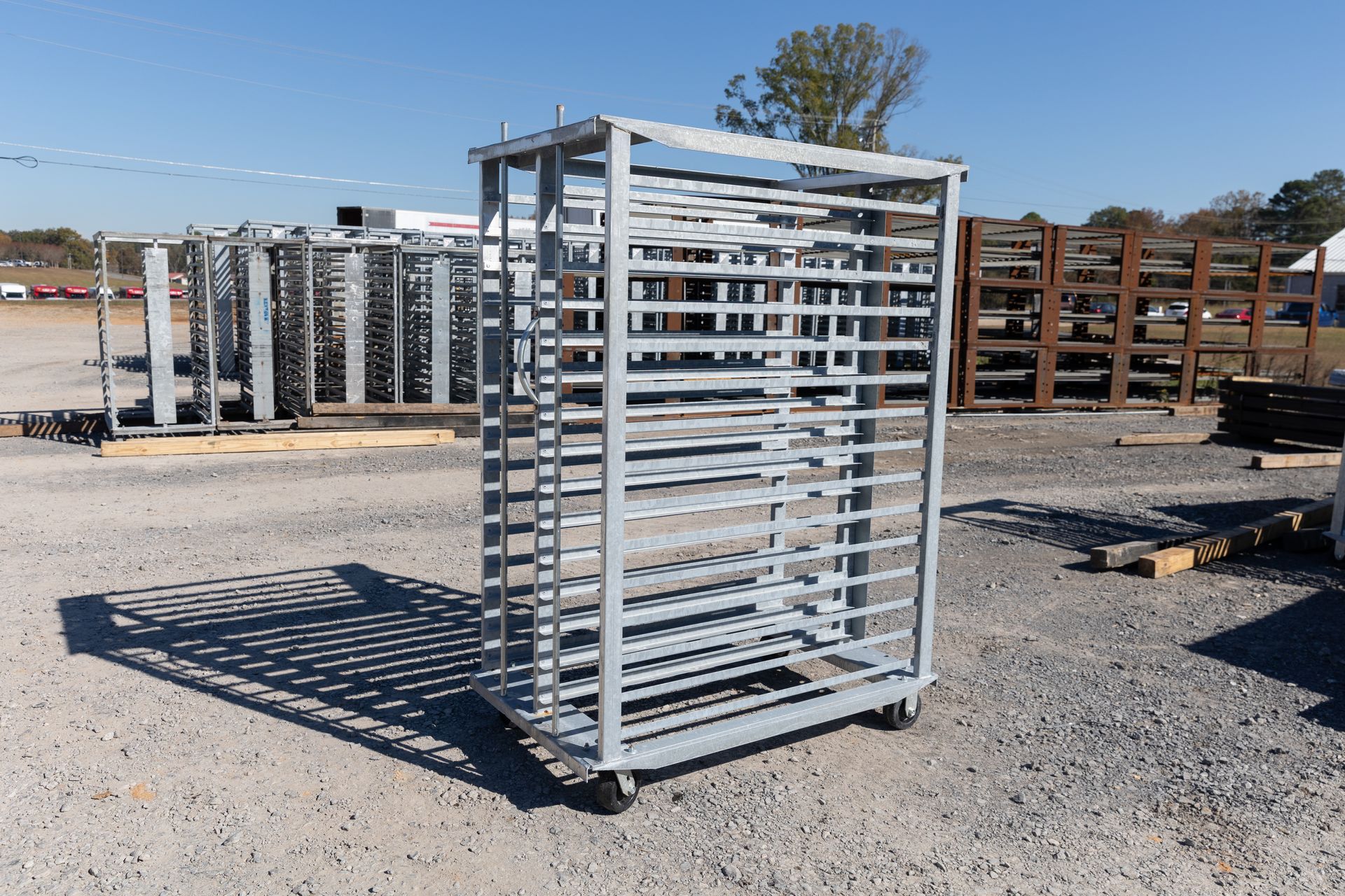 Metal storage racks outdoors. Open metal gate with a handle, other racks in background.