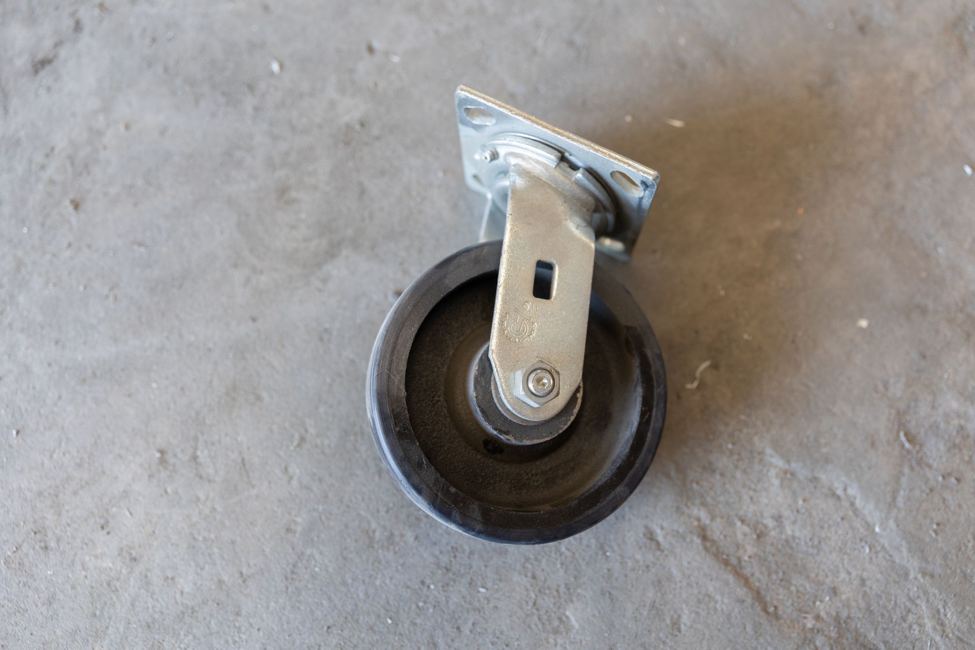 A swivel caster wheel on a gray concrete surface.