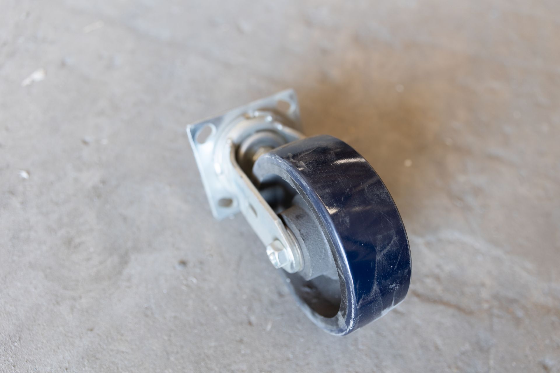 A swivel caster wheel on a gray concrete surface.