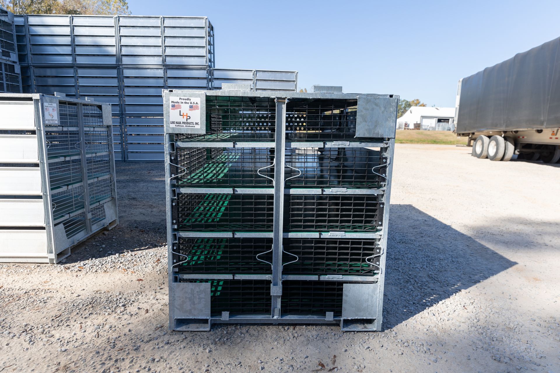 Metal storage container with wire mesh, green racks inside, parked outside.