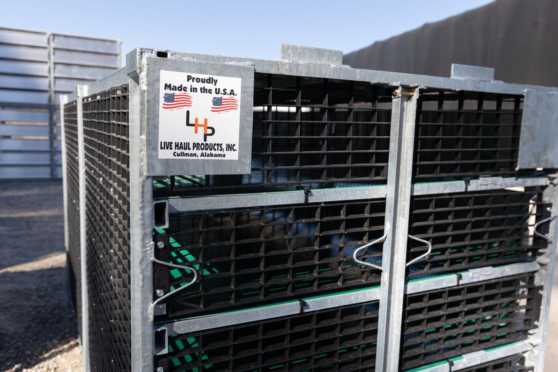 Metal storage container with wire mesh, green racks inside, parked outside.