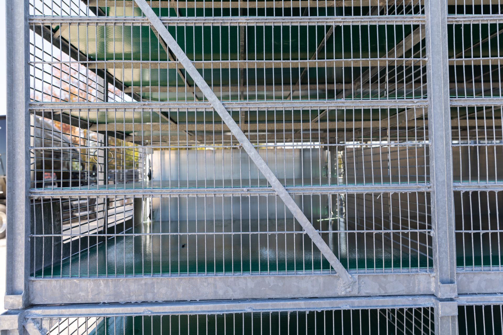 Metal structure with many vertical and horizontal bars; view through the bars of a water-filled container.