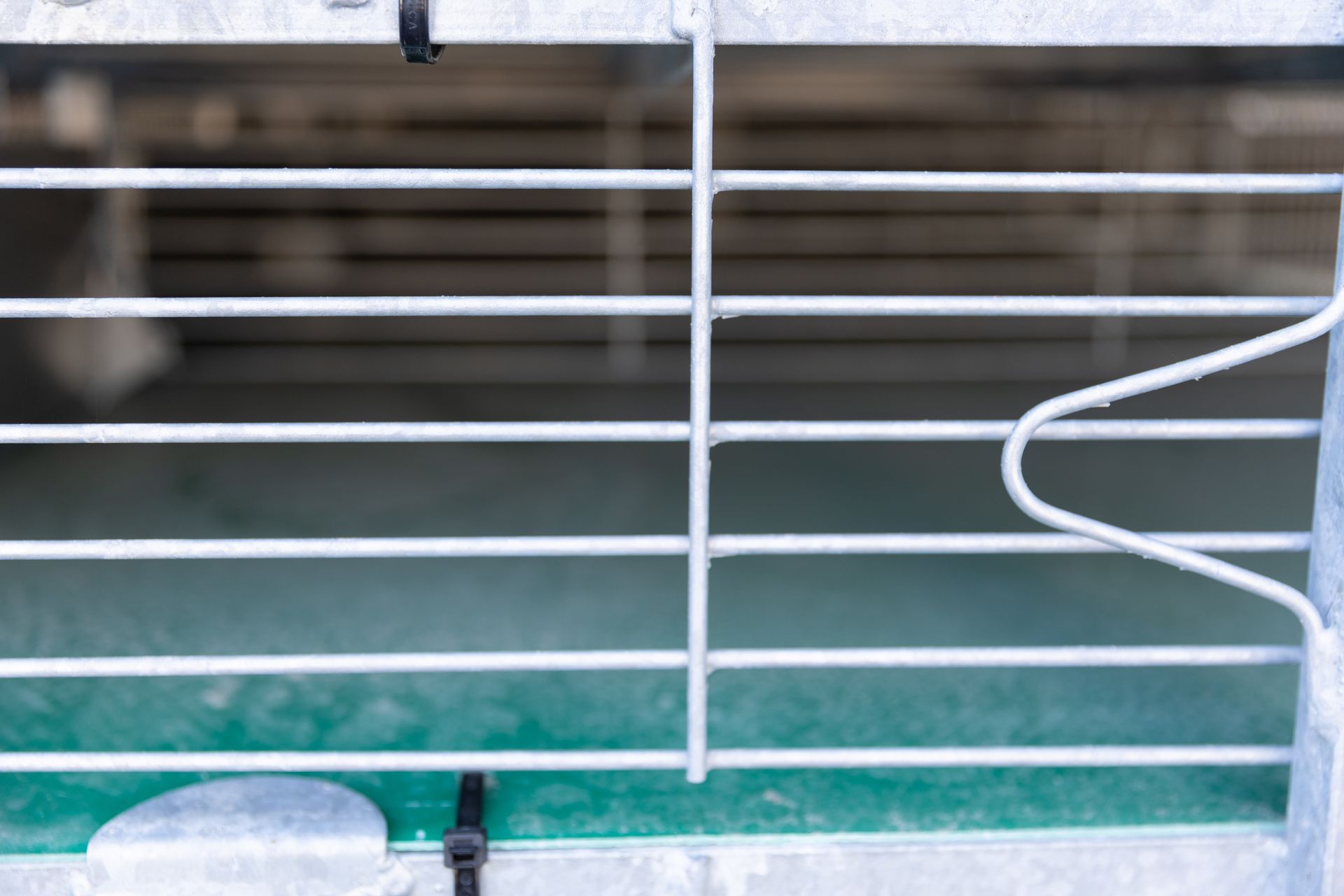 Metal gate with horizontal bars and vertical support, green background.