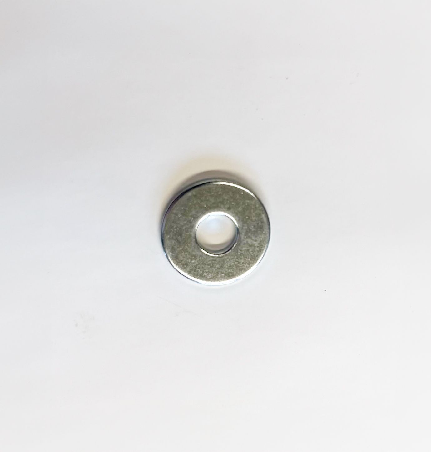 Silver metal washer with a hole in the center, on a white background.