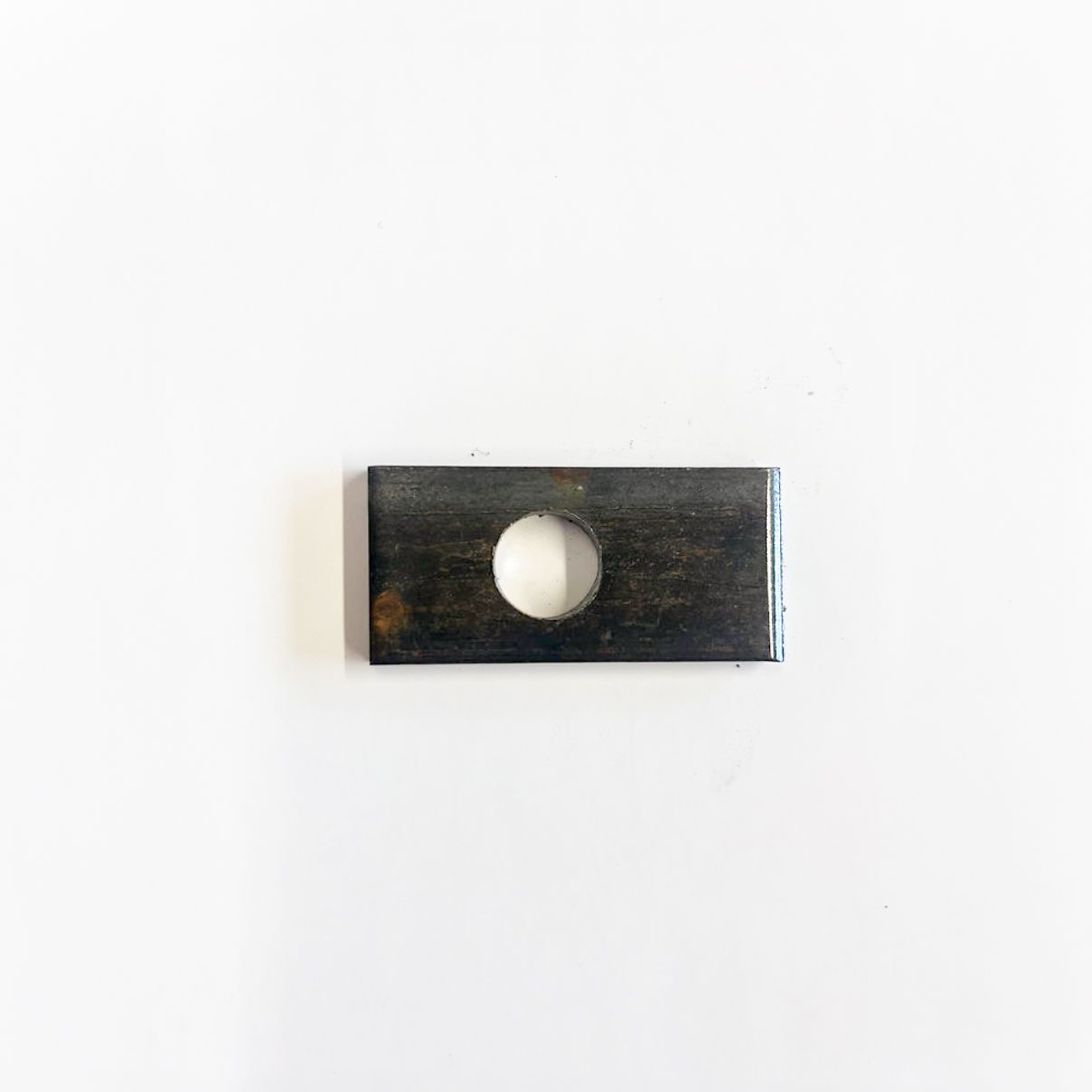 Rectangular metal plate with a centered hole on a white background.