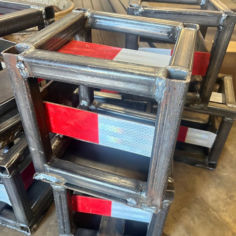 Welded metal frames stacked, with red and silver reflective strips.