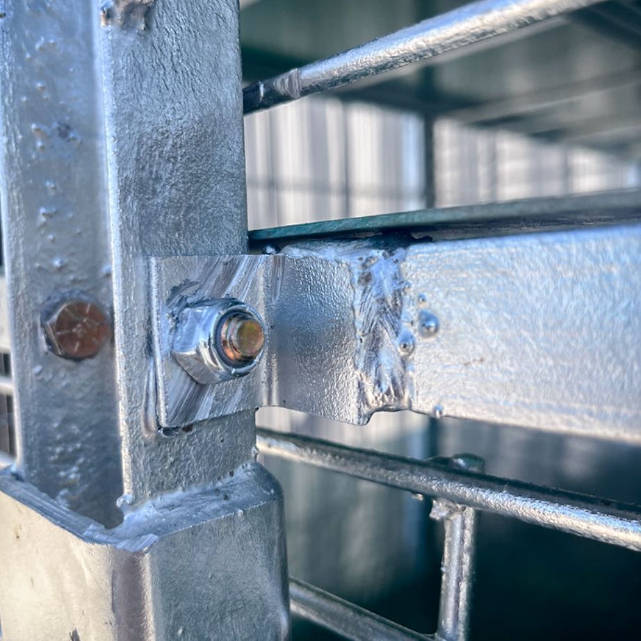 Close-up of a metal structure joint, showing a bolted connection and welding in a galvanized finish.