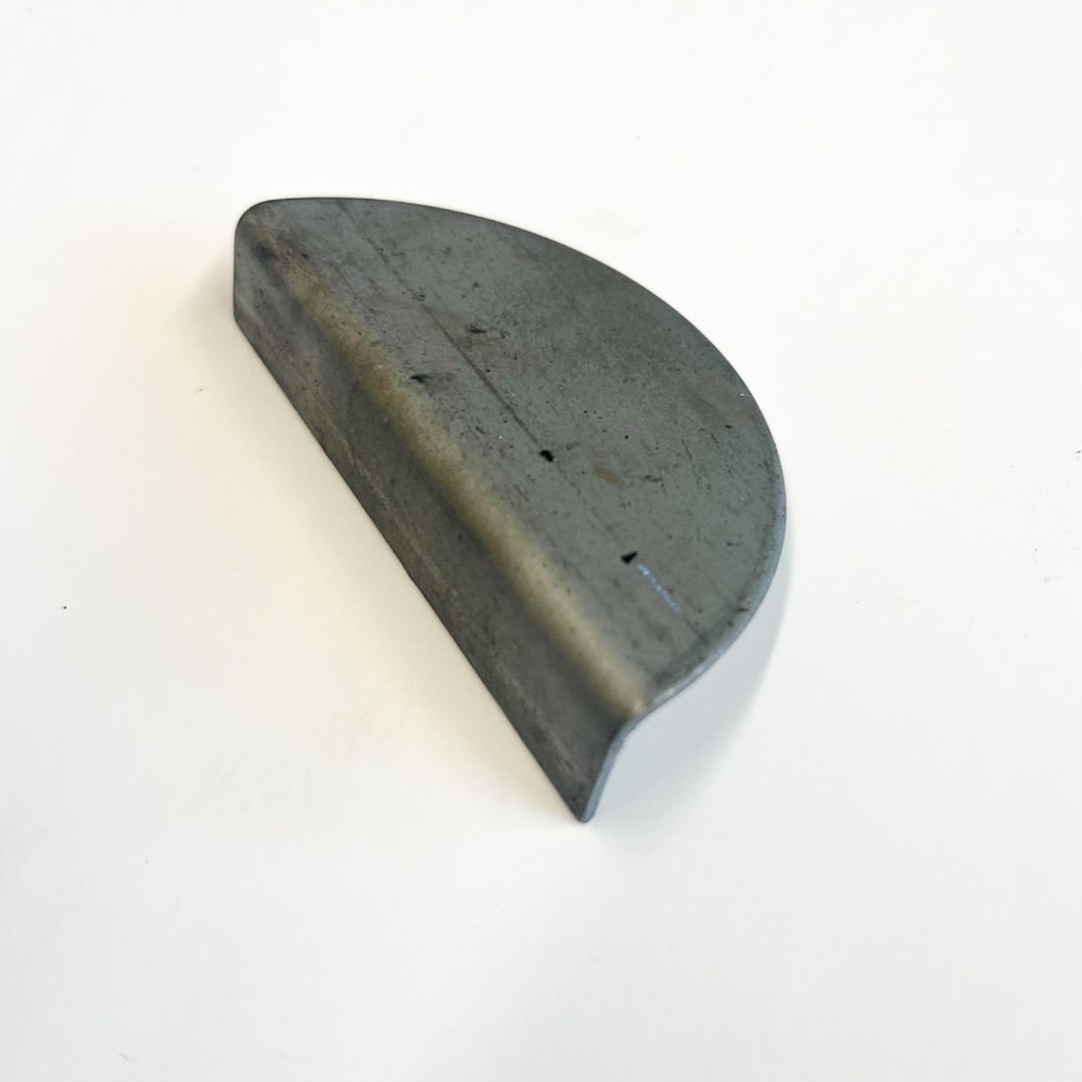 Metal, curved corner piece with a bent edge, possibly part of a structure or machine.