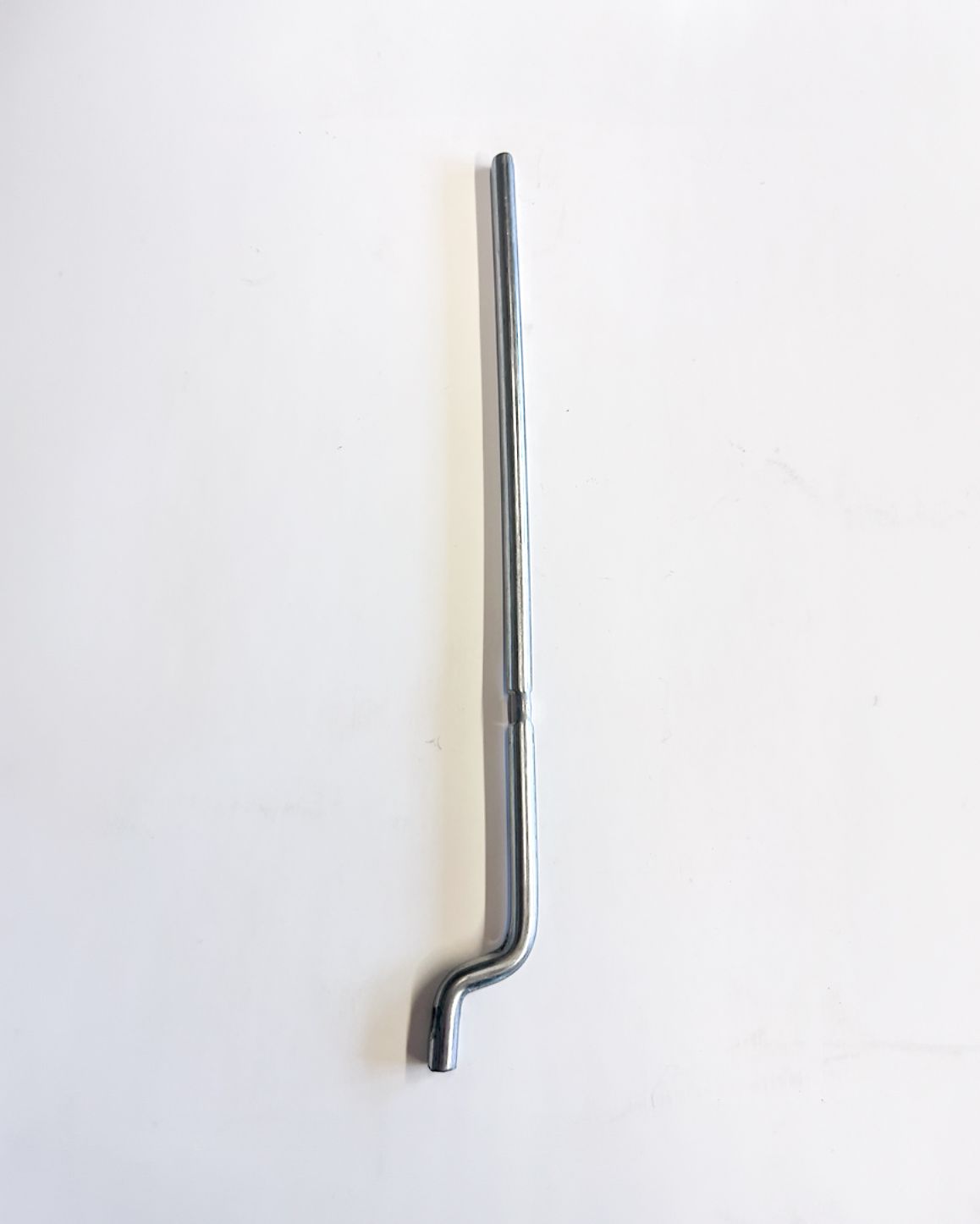 Silver metal rod with a bent end, lying on a white surface.