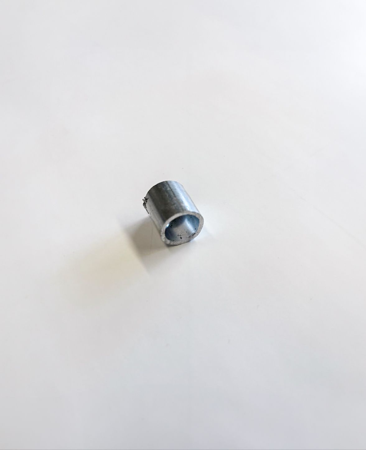 Small, metallic, cylindrical object on a white background.
