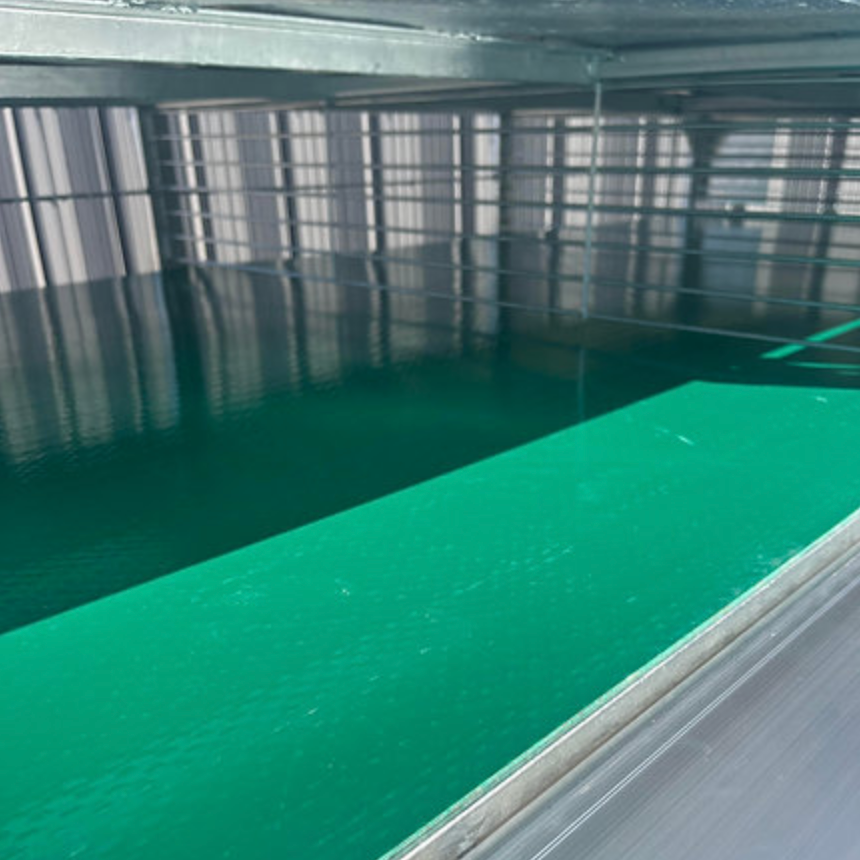 Green-painted surface with reflections, beneath a metal structure, adjacent to a wall of vertical lines.