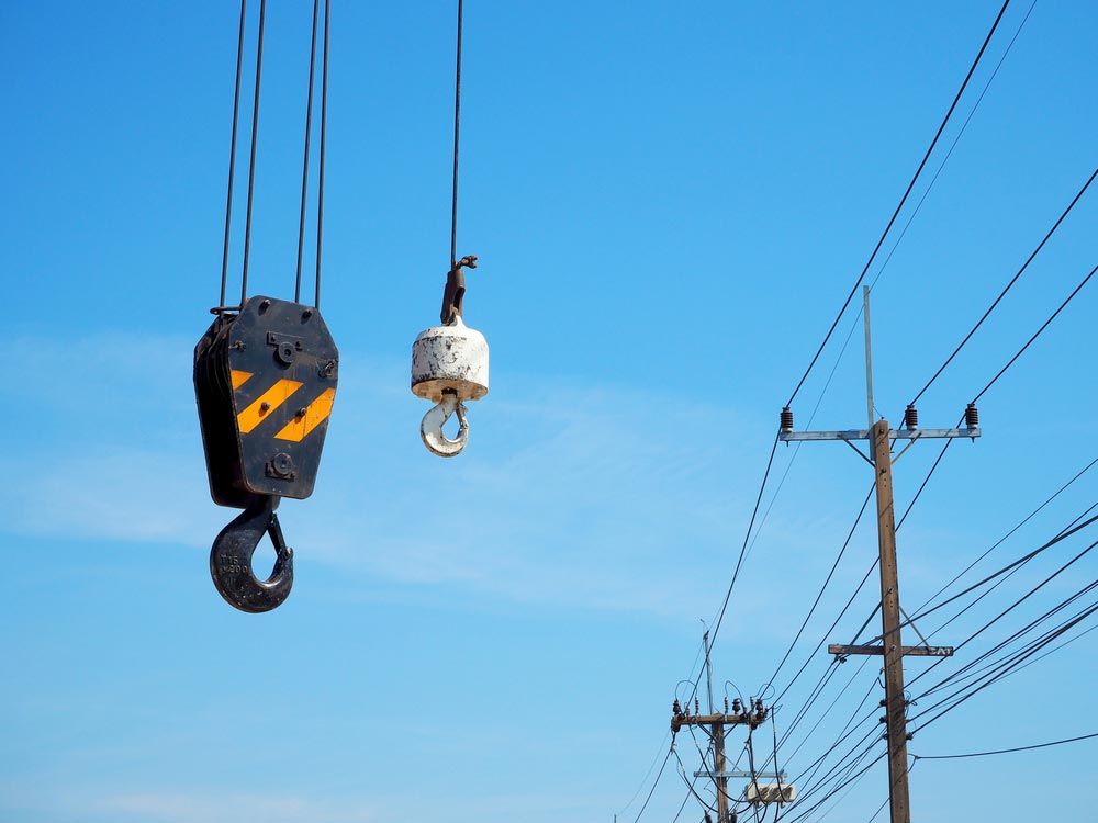 Crane Hook On The Blue Sky With Electricity Cable — Lifting Equipment in Gympie, QLD