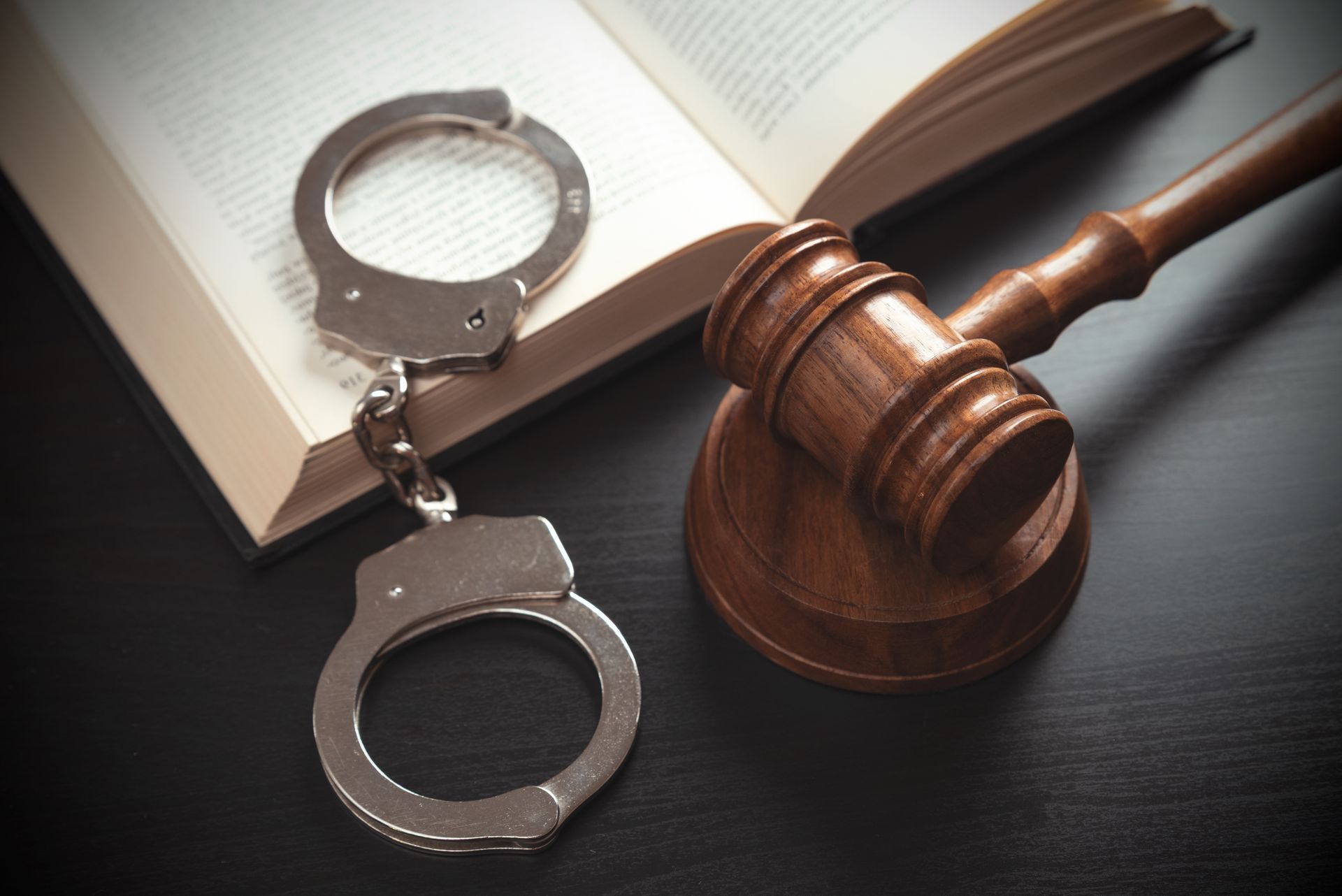 Handcuffs, gavel, and open book, symbolizing law and justice.