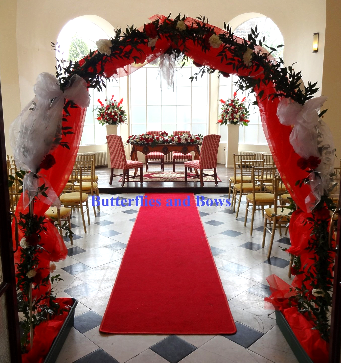 Red & white drapes and flowers frame the entrance to a boldly styled wedding ceremony