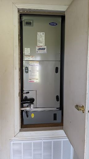 An air conditioner is sitting inside of a doorway in a room.