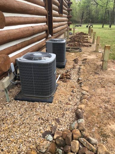 Two air conditioners are sitting on the side of a log cabin.