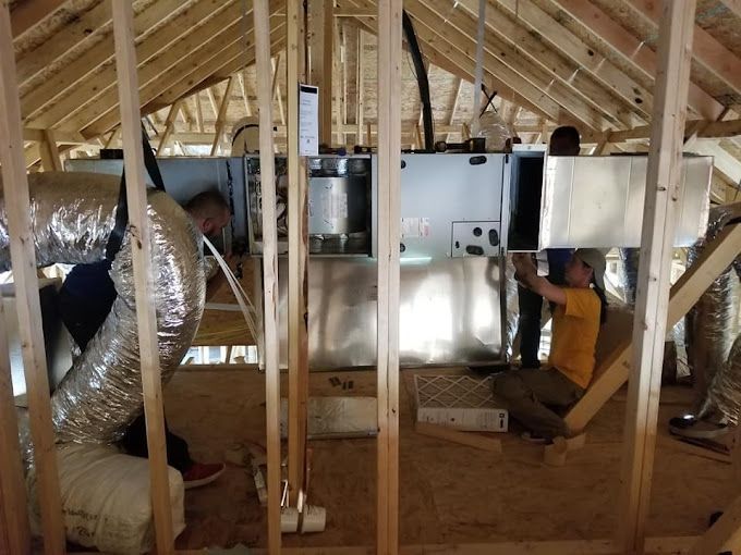 A man in a yellow shirt is working in the attic of a house