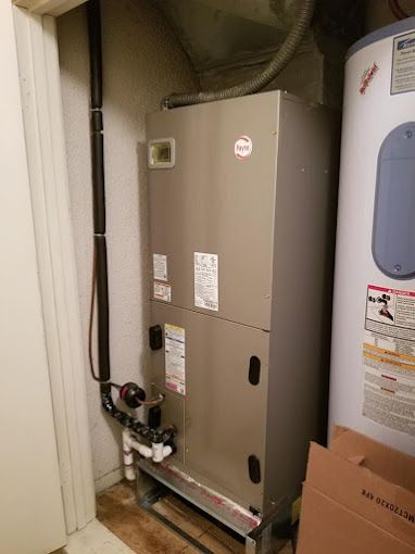 An air conditioner is sitting next to a water heater in a room.