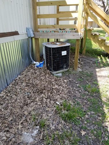 An air conditioner is sitting on the side of a house next to stairs.