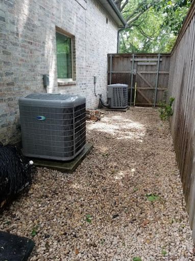 There are two air conditioners in the backyard of a house.